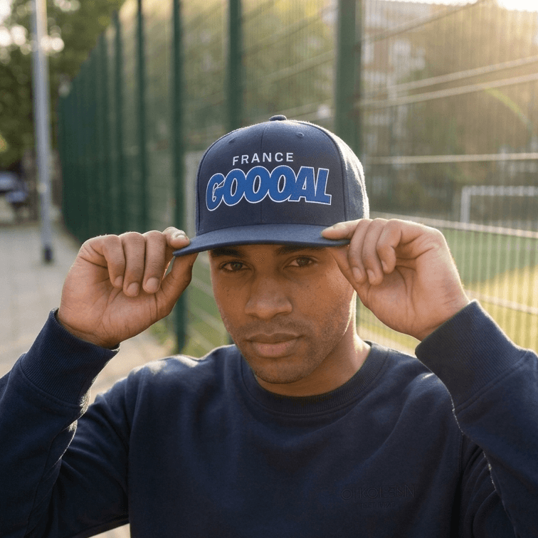 Person wearing a navy blue cap with 'France GOOOAL' text, standing outdoors.