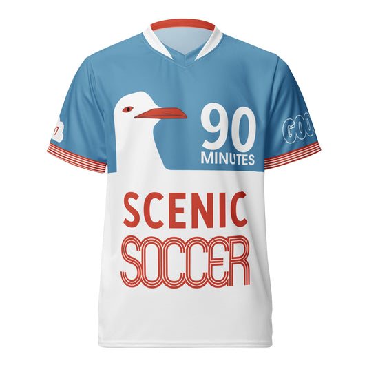 A short-sleeve soccer jersey with a light blue upper section, white lower section, red trim, a large white goose graphic, and the text '90 MINUTES' and 'SCENIC SOCCER'.