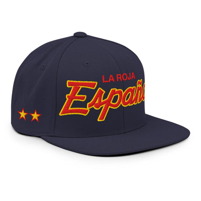 A navy blue flat-brim baseball cap with 'LA ROJA Espana' embroidered on the front in red and yellow, featuring two yellow stars on the side, set against a plain white background.