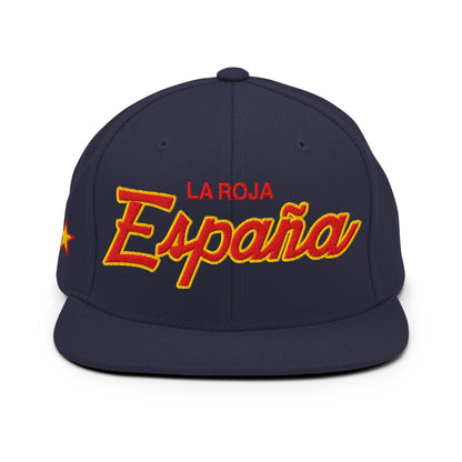 A navy blue snapback cap featuring 'LA ROJA España' embroidered on the front in red and yellow, with a small yellow star on the side, set against a plain white background.
