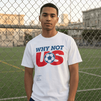 Person wearing a white t-shirt with 'Why Not US' design on a soccer field.